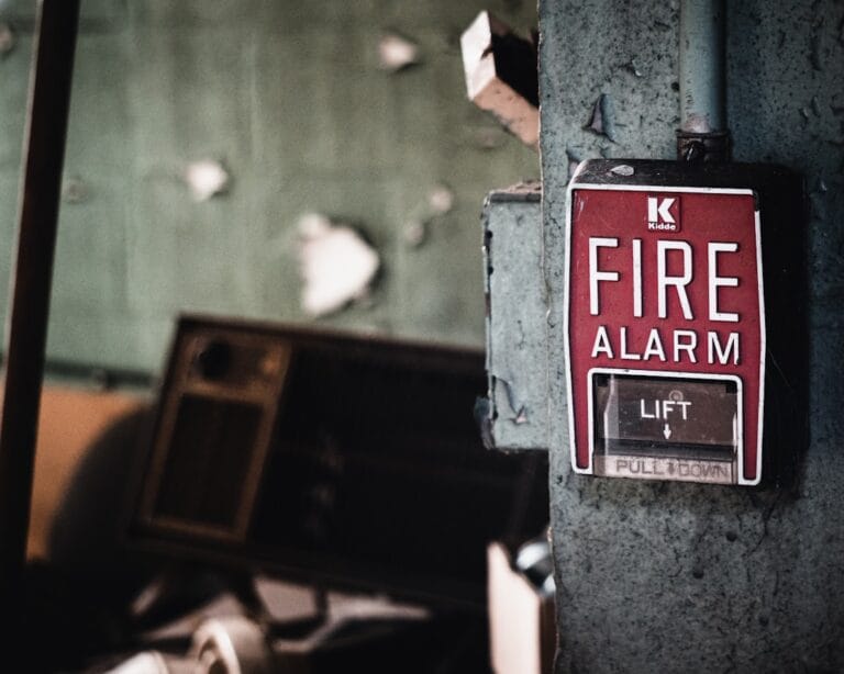 a red fire alarm sign mounted to the side of a metal pole