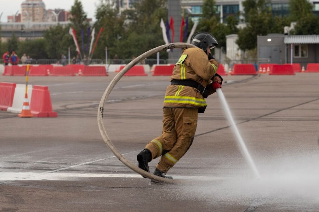 Firefighter sprays water through a large hose loop.