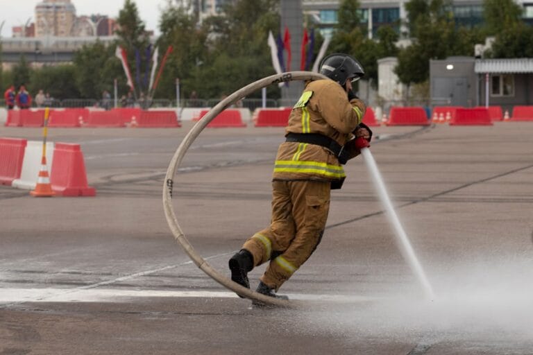 Firefighter sprays water through a large hose loop.