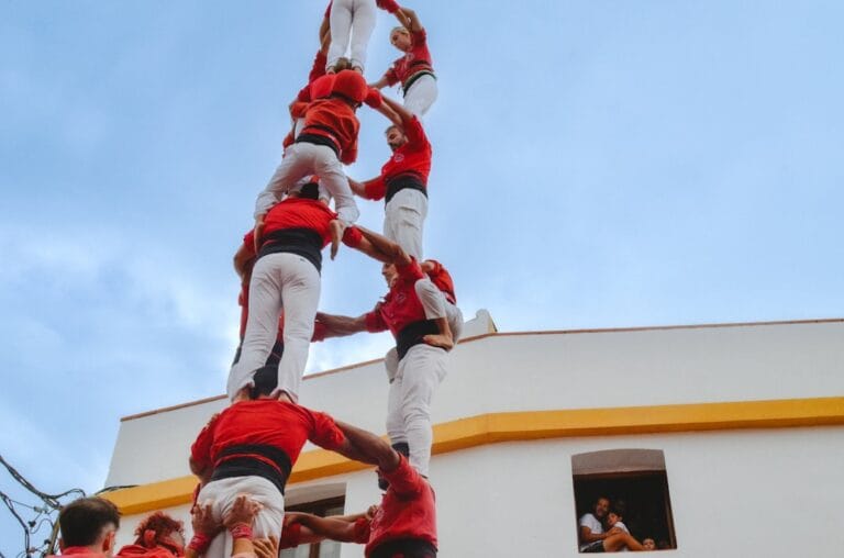 People form a human tower against a cloudy sky.
