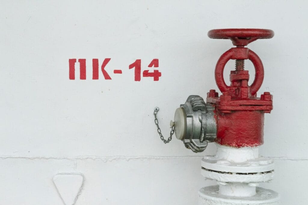 red and white fire hydrant beside white wall