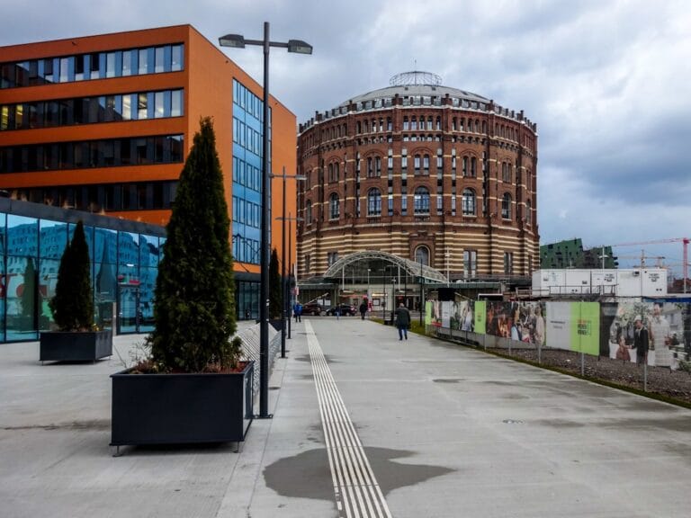 Modern orange building next to historic brick gasometer.